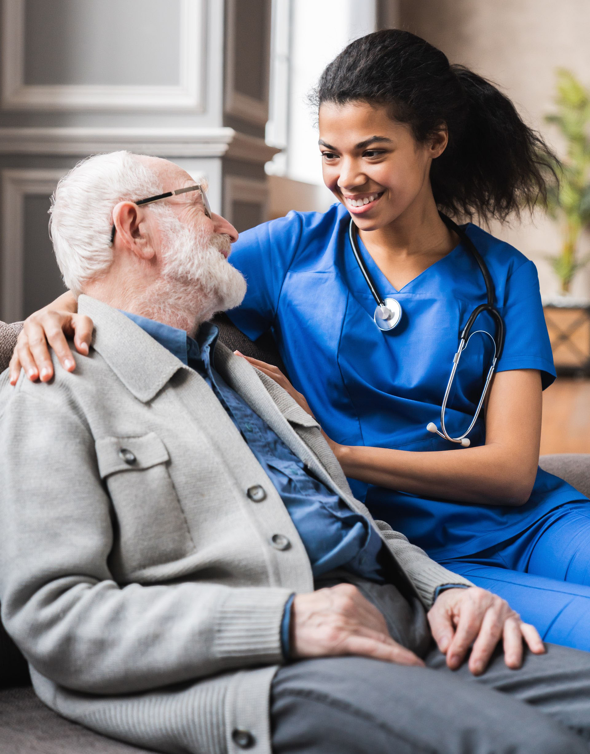 Vertical photo of helpful young female doctor nurse consulting old elderly man . 80s senior man talking about health condition and medicine with woman general practitioner.